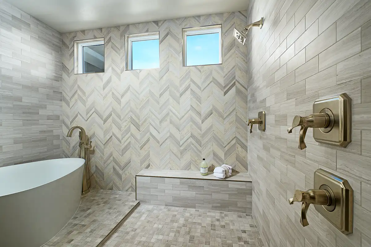 Plumbing fixtures: Open shower with herringbone and horizontal tan/brown tile in with gold fixtures